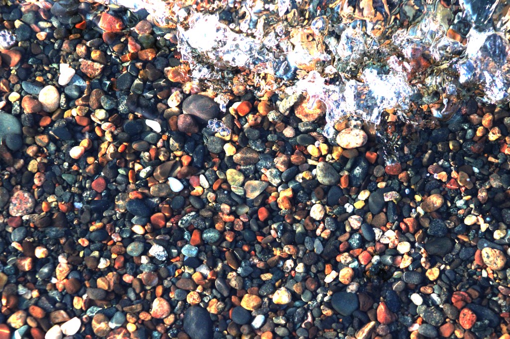 Colorful pebbles on the Lake Superior shore with clear water washing over the rocks